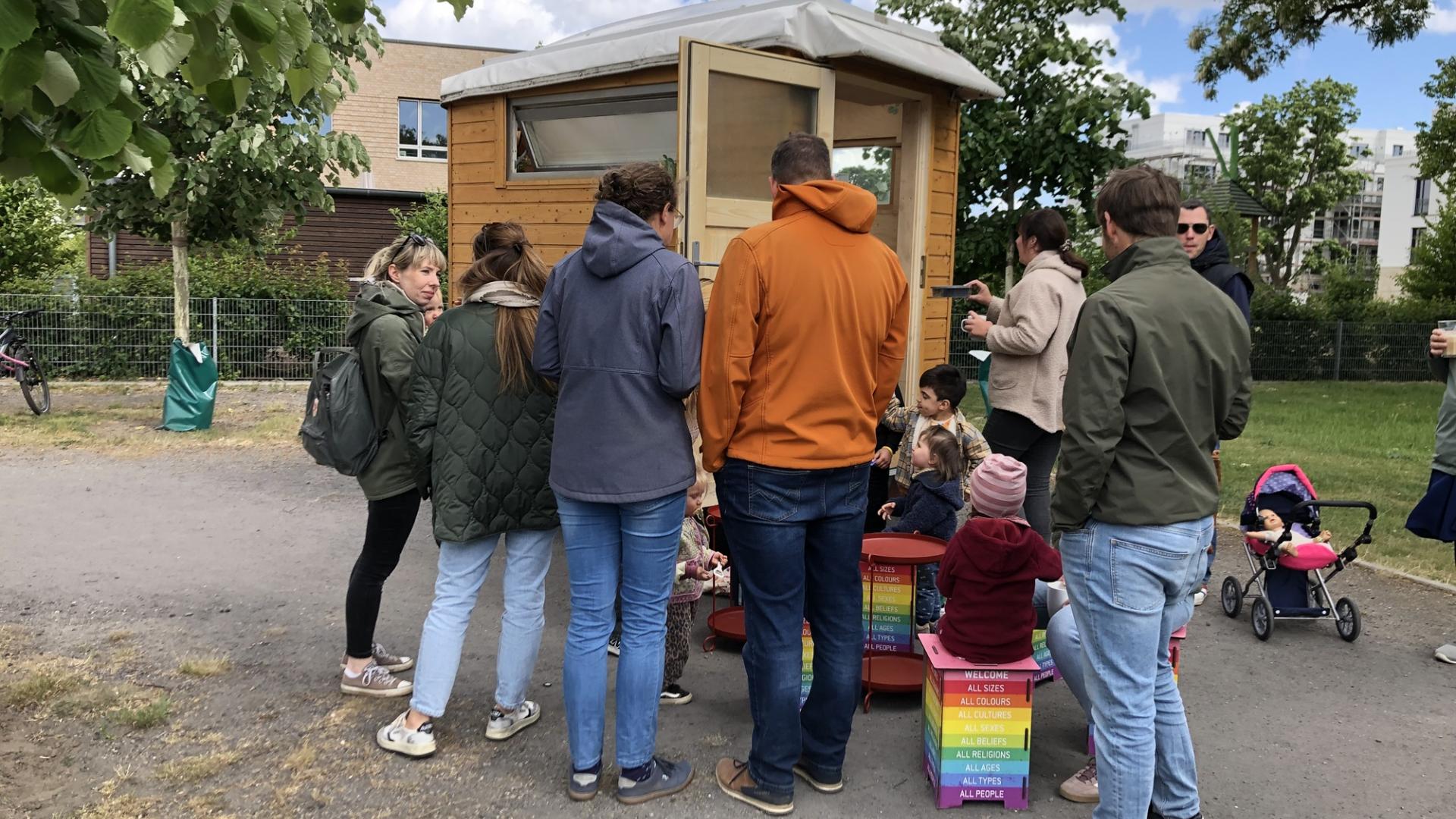 Mehrere Menschen drängen sich um eine winzige Hütte.