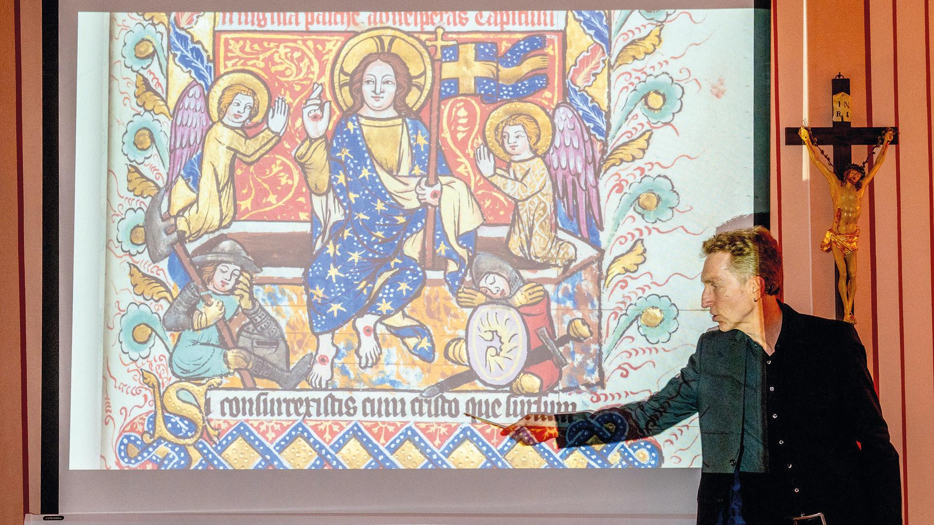 Ein Mann erklärt eine farbprächtige Handschrift aus der Klosterbibliothek in St. Marienstern