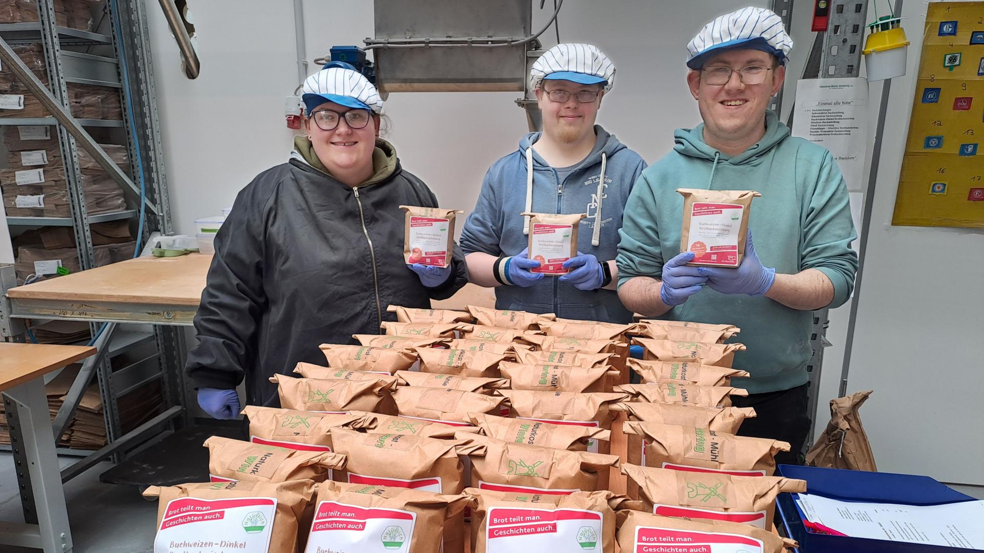 Drei Menschen vor einem Haufen Brotbackmischungen