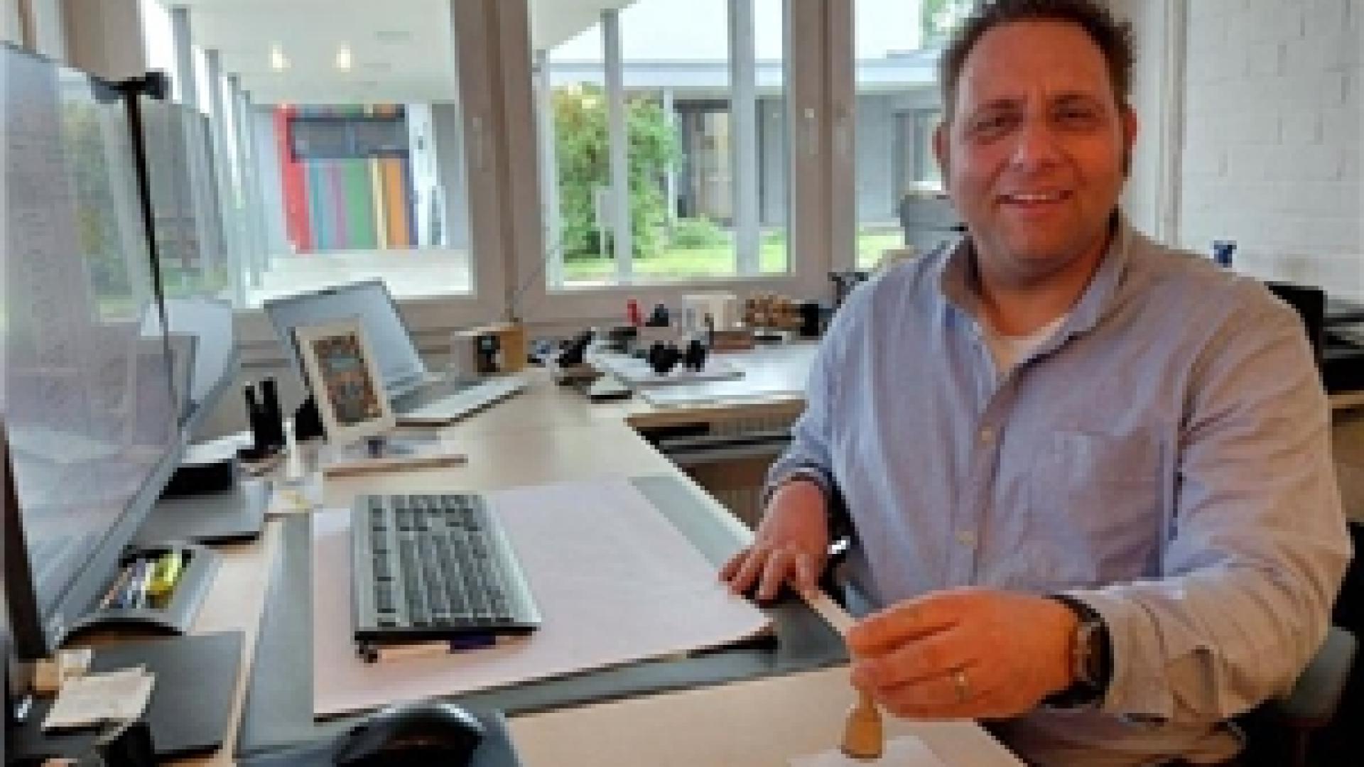 Ein Mann sitzt in einem Büro und hält einen Stempel in der Hand