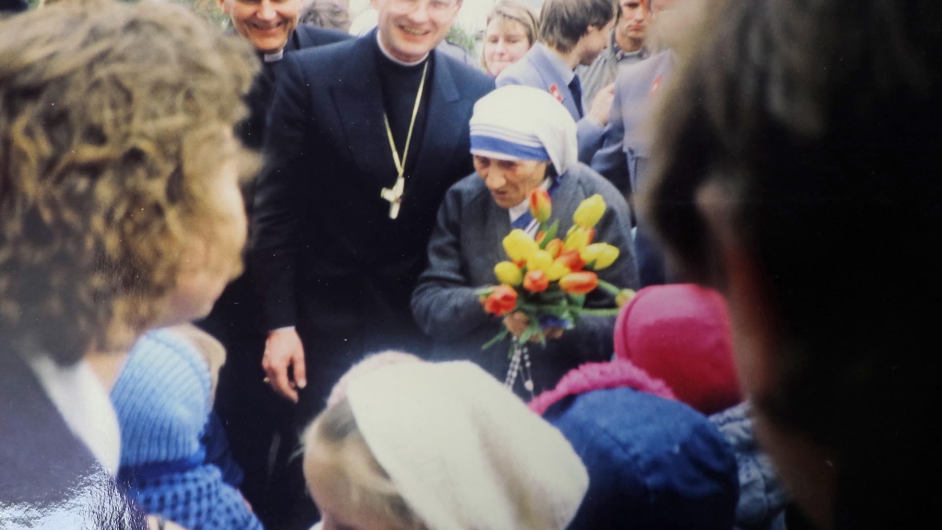 Eine Frau steht in einer Menschenmasse mit einem Strauß Blumen in den Händen.