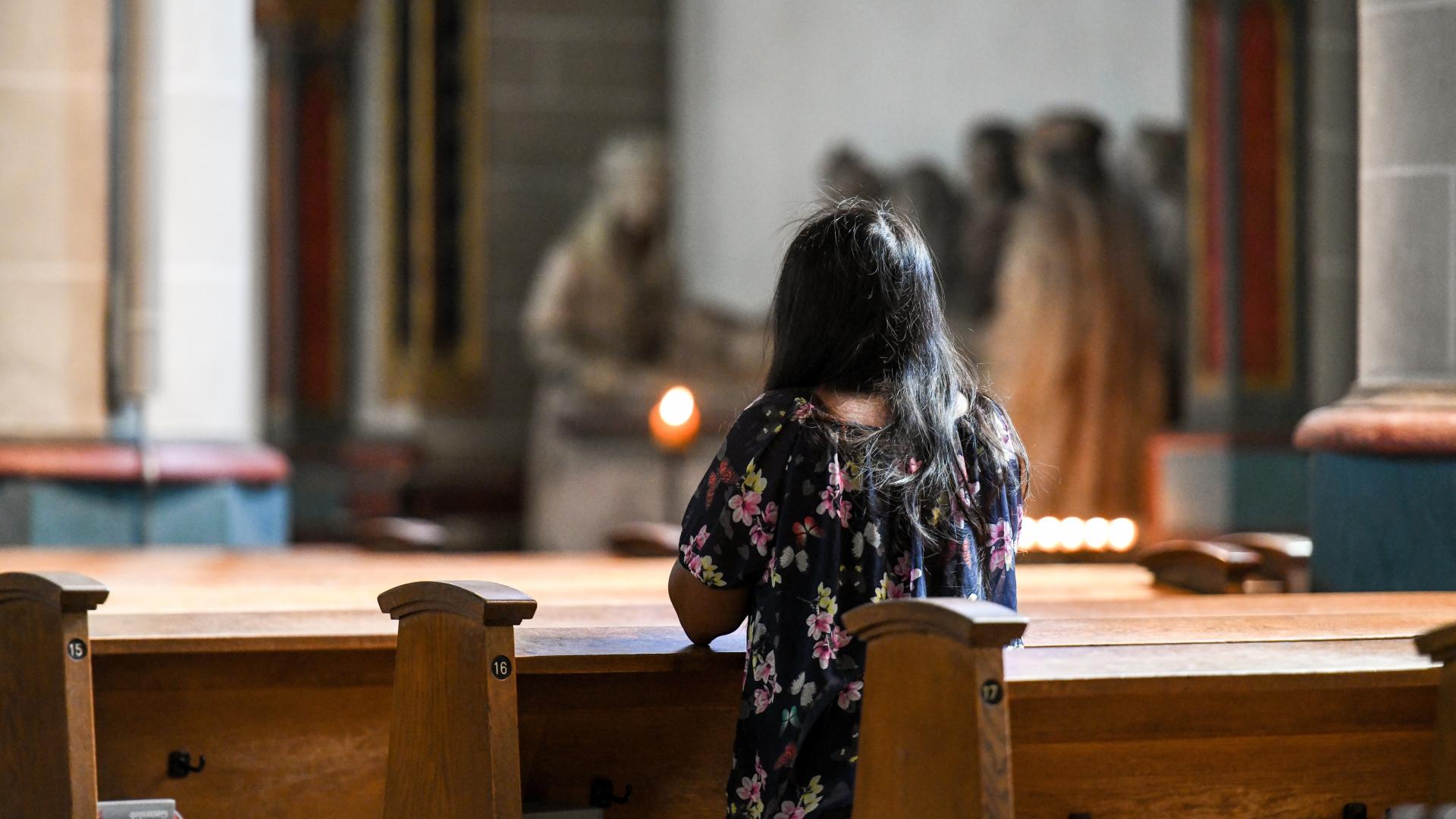 Frau, die in einer Kirchenbank kniet