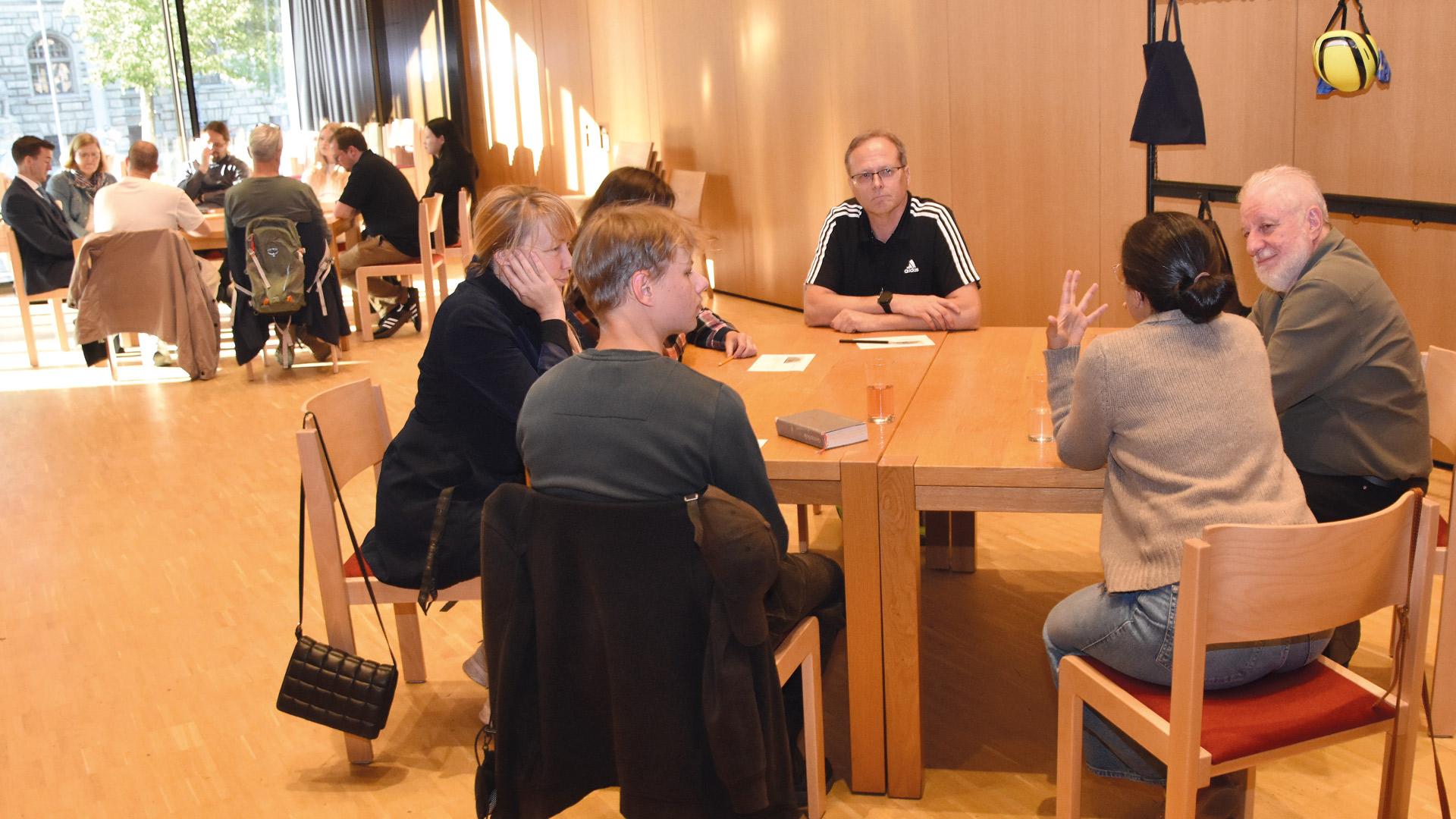 eine Gruppe von Menschen sitzen an einem Tisch und unterhalten sich