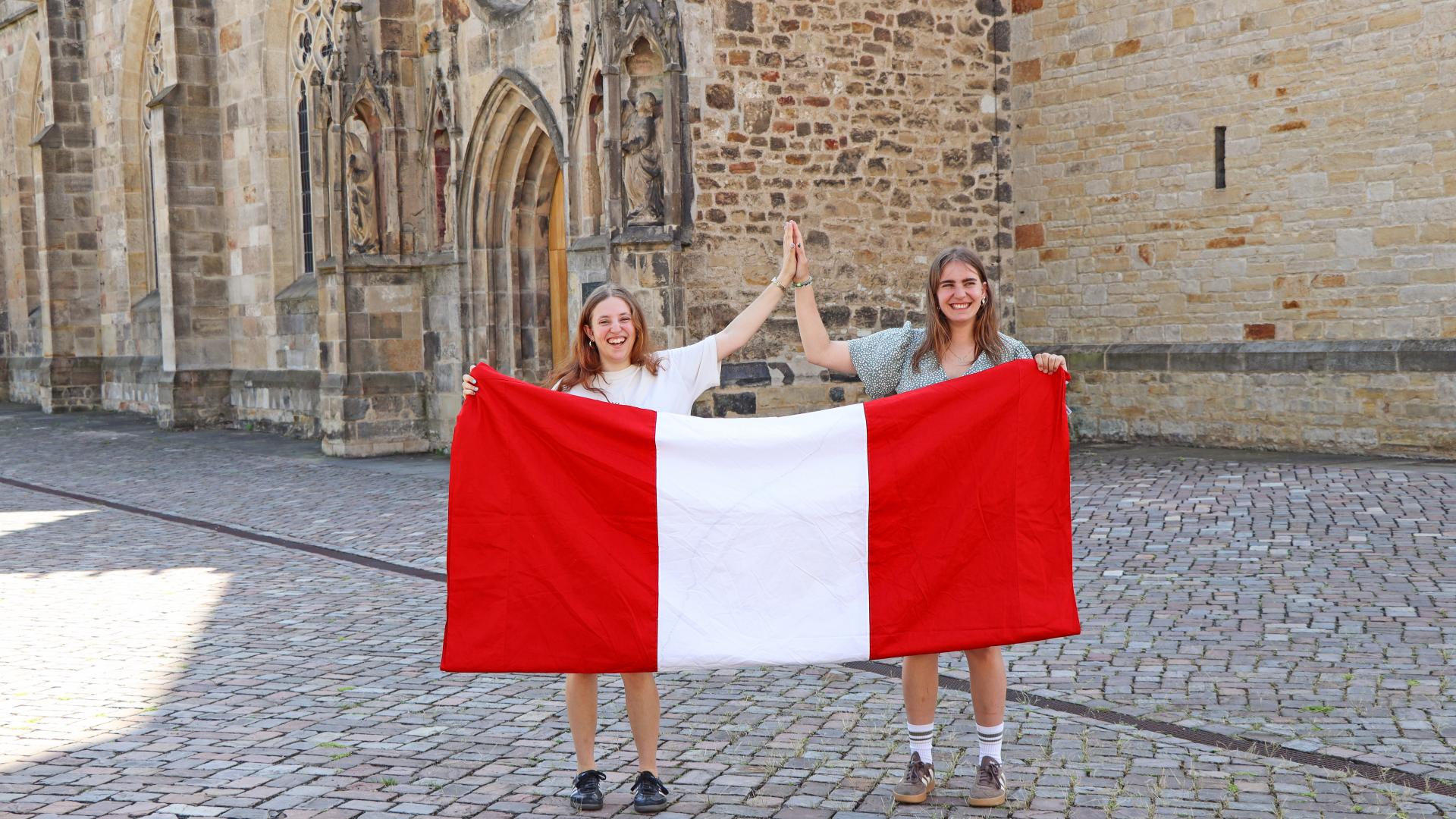 Zwei junge Frauen vor einer Peru-Flagge