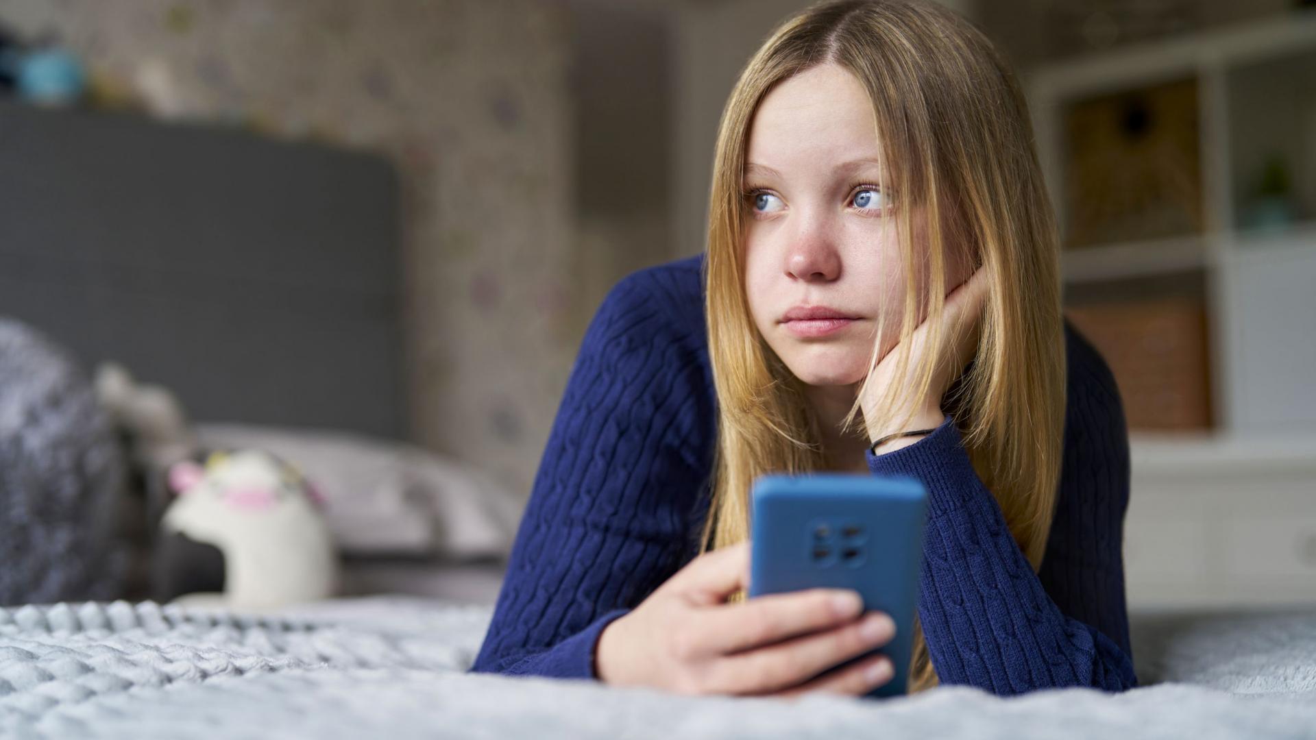 Mädchen traurig mit Smartphone