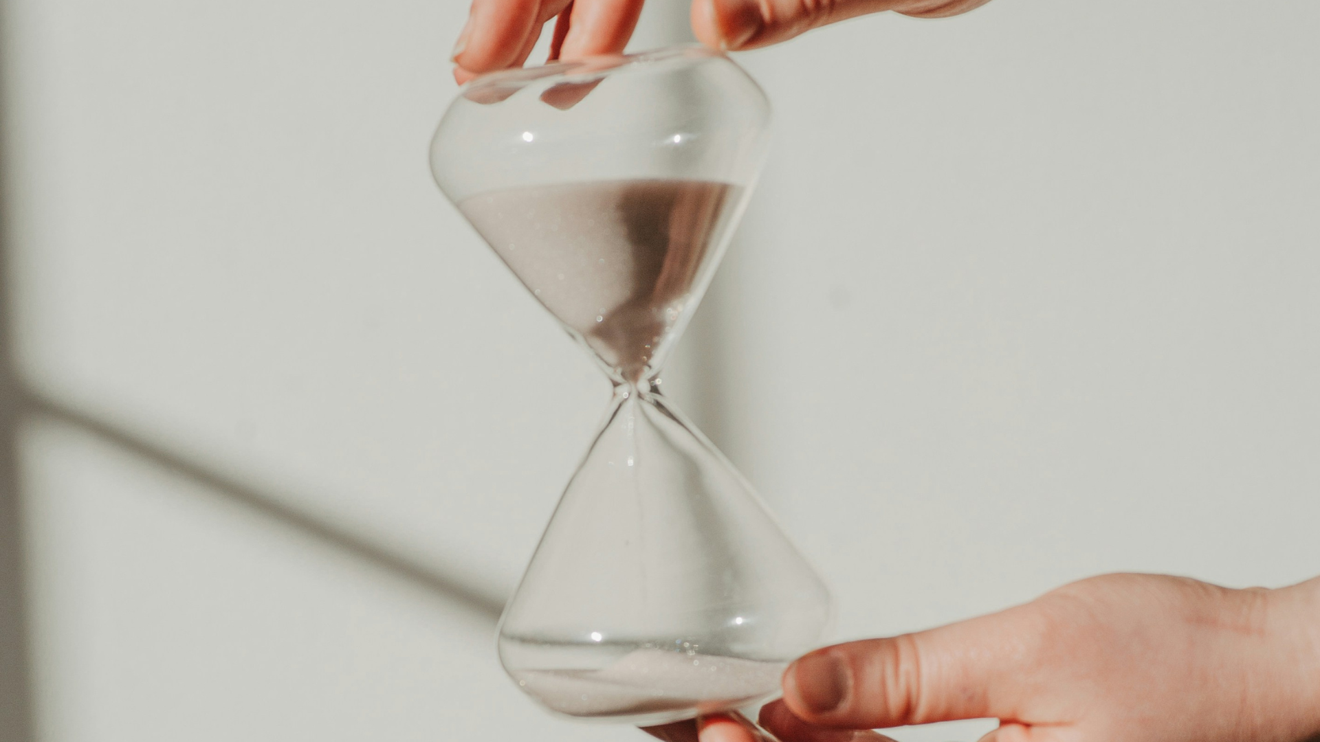 Sanduhr vor einer beigen Wand