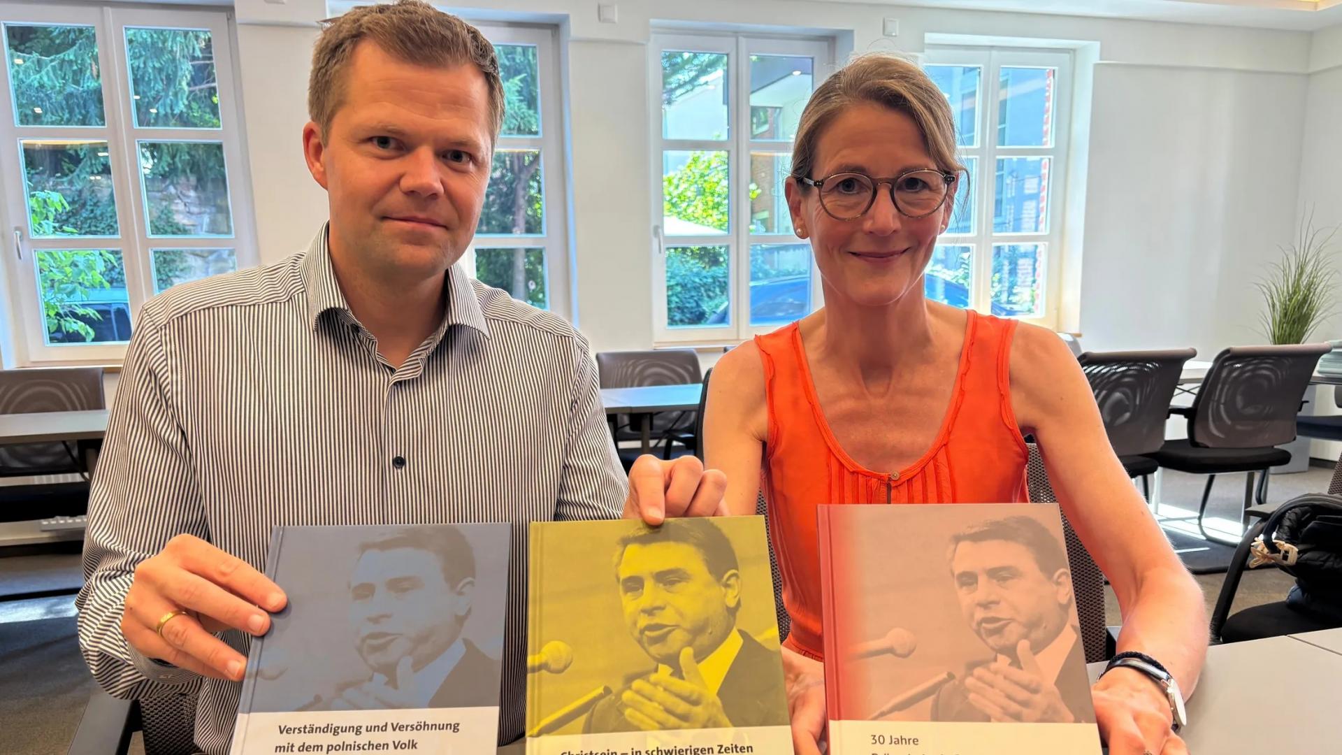 Zwei Personen halten Bücher in die Kamera
