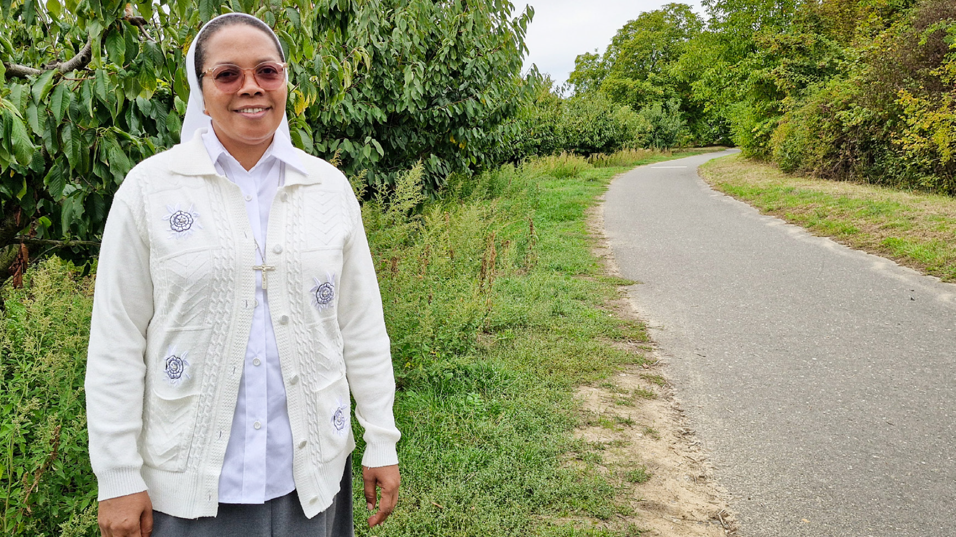 Eine Frau vor einer Straße und grünen Büschen
